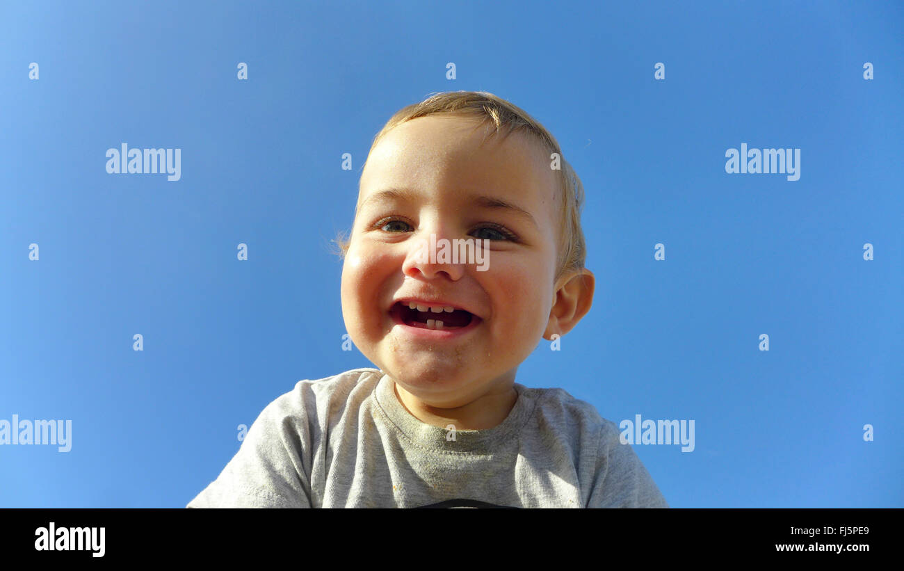 Kleinkind lachen vor blauem Himmel, Porträt eines Kindes Stockfoto