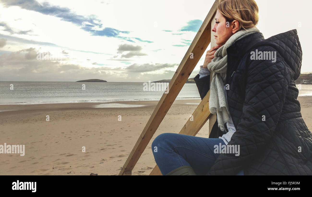 junge Frau sitzt auf Holztreppen am Strand Stockfoto