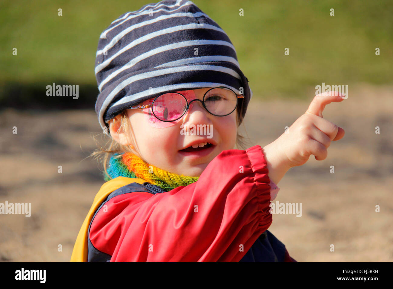 kleines Mädchen mit Brille und eine Augenklappe zeigen mit dem Finger auf etwas, Deutschland Stockfoto