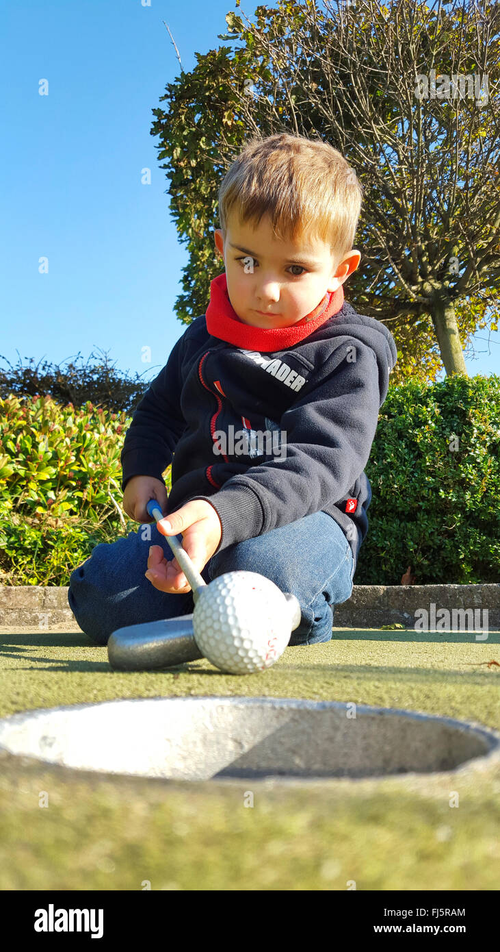 kniende kleine Junge holing einen Ball, Minigolf, Deutschland Stockfoto