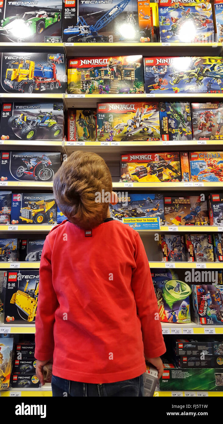 kleiner Junge bewundern ein Spielzeug-Regal mit LEGO-Packungen Stockfoto