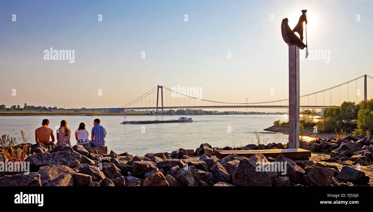 vier Personen in eine Skulptur am Rhein-Ufer, transportieren, Schiff und Brücke im Hintergrund, Deutschland, Nordrhein-Westfalen, Niederrhein, Emmerich Stockfoto