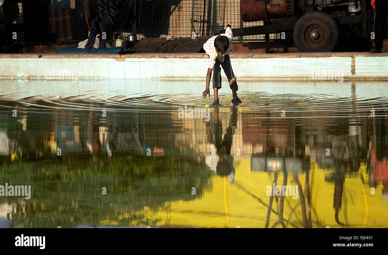 junge Kommissionierung einen Tennisball aus dem Wasser, Indien Stockfoto