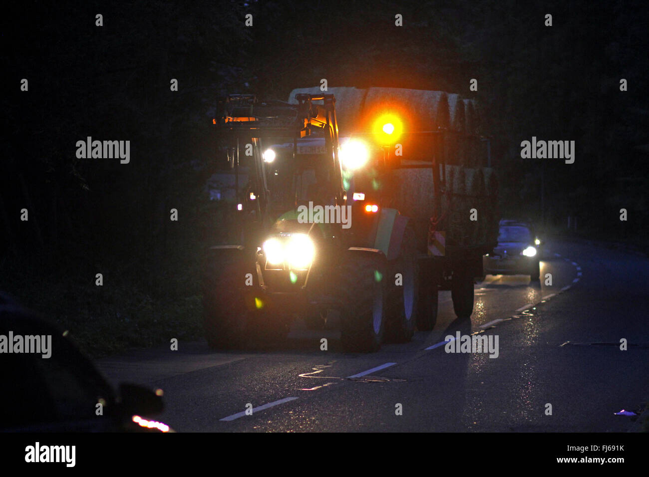 Traktor Transport von Stroh Kugeln am Abend, Deutschland Stockfoto