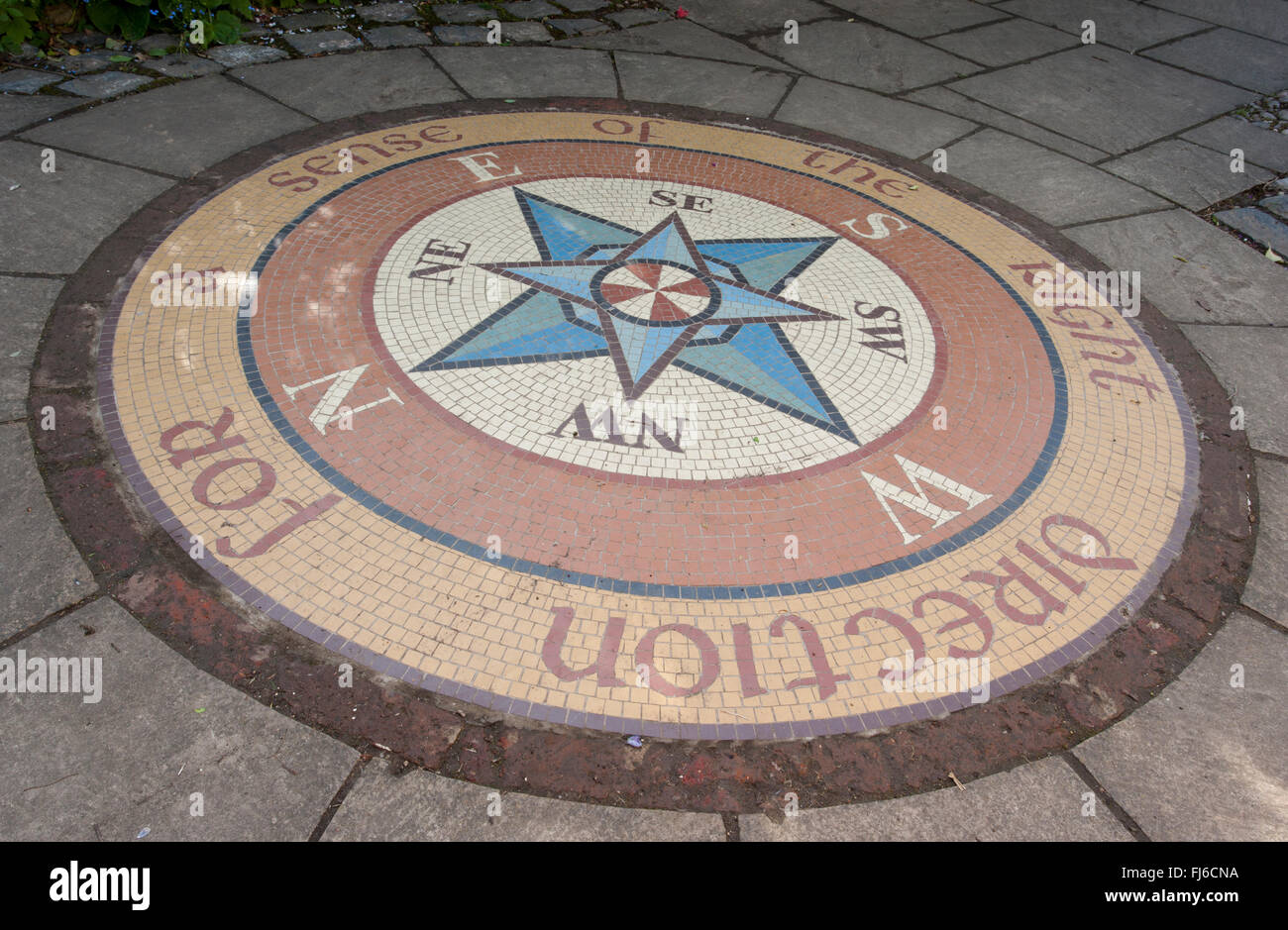 Kleine kreisförmige Terrasse Garten mit einem Kreis Kompass gefliesten Fliesen Mosaik in einem Stein gepflasterten Innenhof zeigt Richtungen UK gesetzt Stockfoto