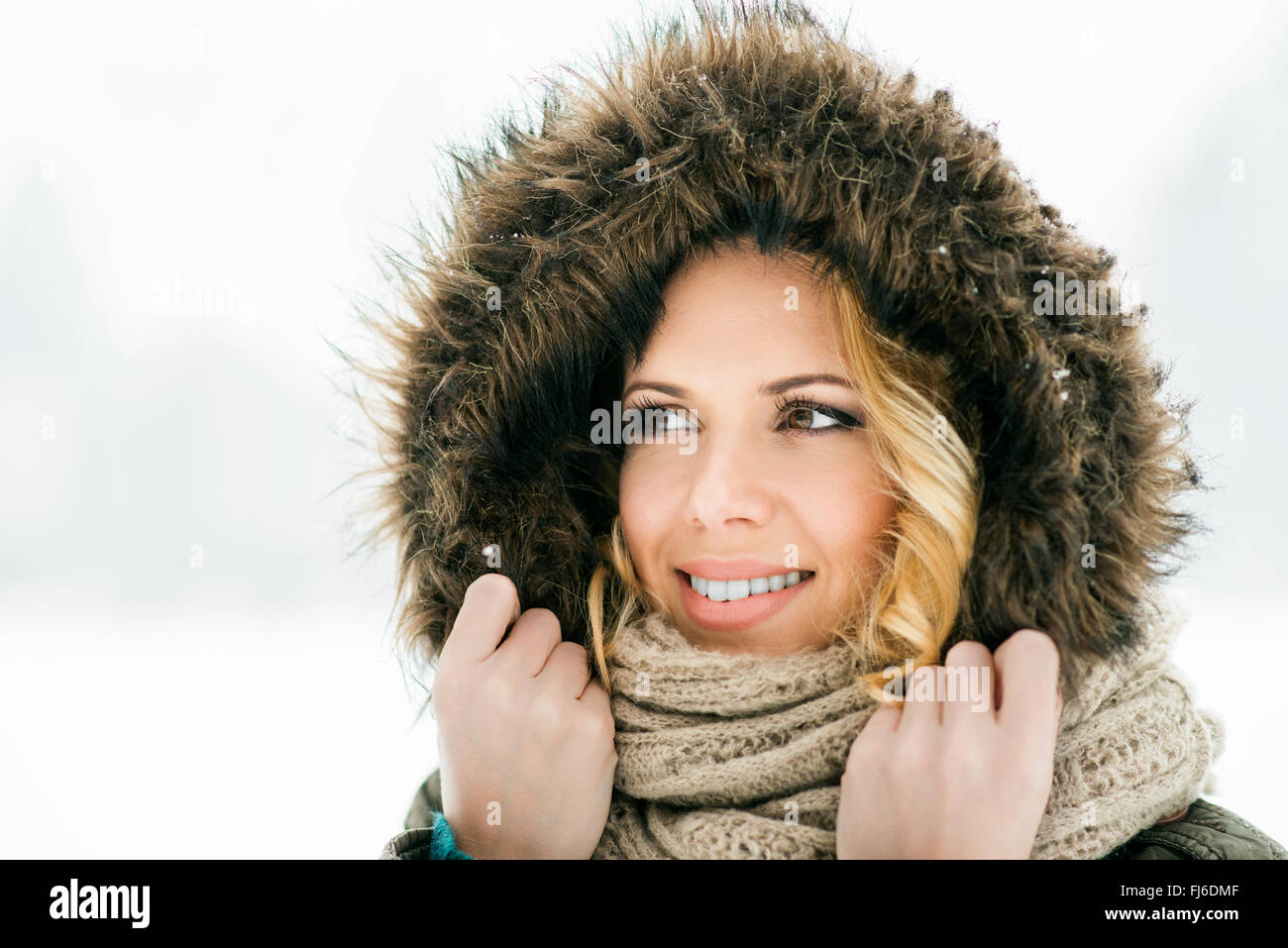 Frau im Fell Kapuze und Schal, verschneite Winterlandschaft Stockfoto