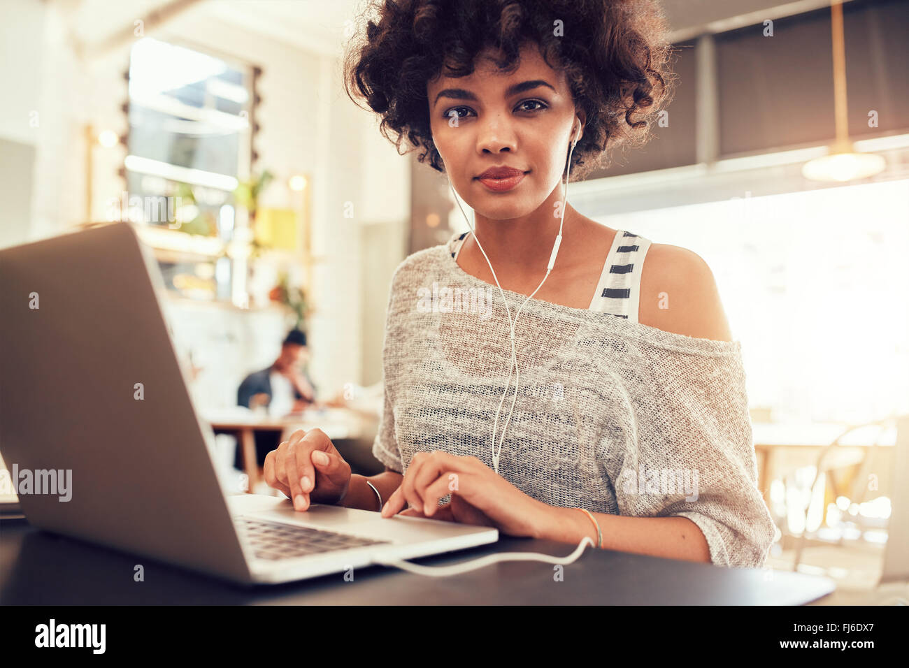 Porträt der jungen Frau mit Laptop im Café. Afrikanische Frau im Coffee-Shop mit einem Laptop. Stockfoto