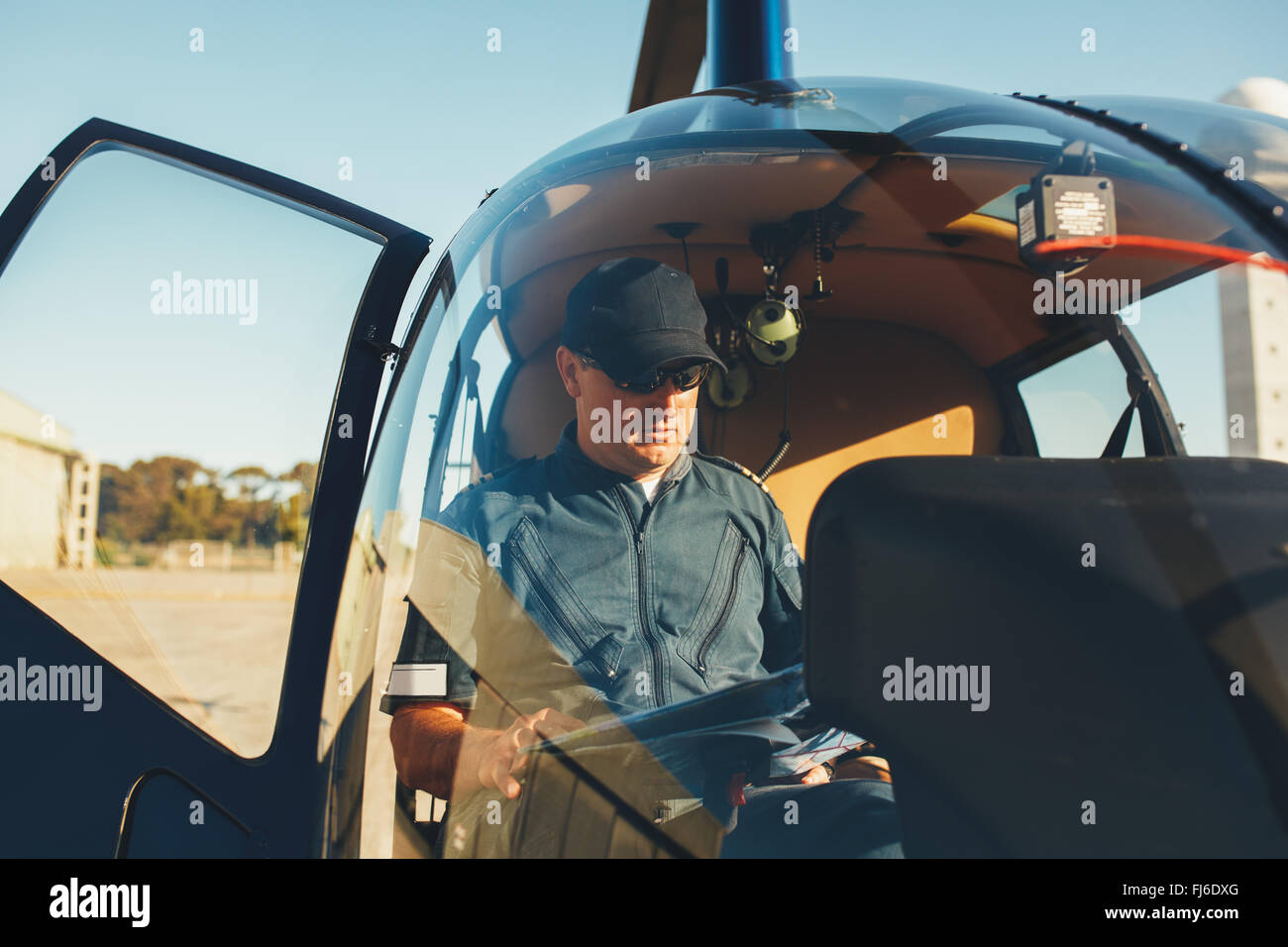Piloten, die Karte zu lesen, während sitzen im Cockpit eines Hubschraubers. Hubschrauber am Flughafengelände. Stockfoto