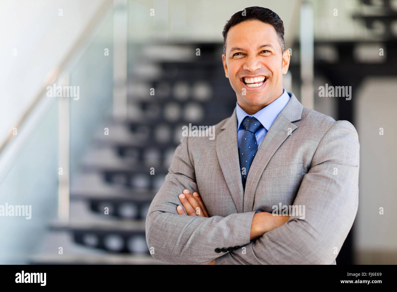 fröhliche Geschäftsmann mit Armen gefaltet in modernen Büro Stockfoto