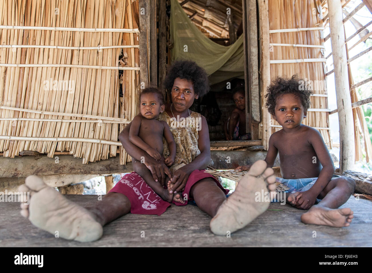 Einheimische Frau mit Kindern durch ihr Haus Kuiawa, Papua-Neuguinea Stockfoto