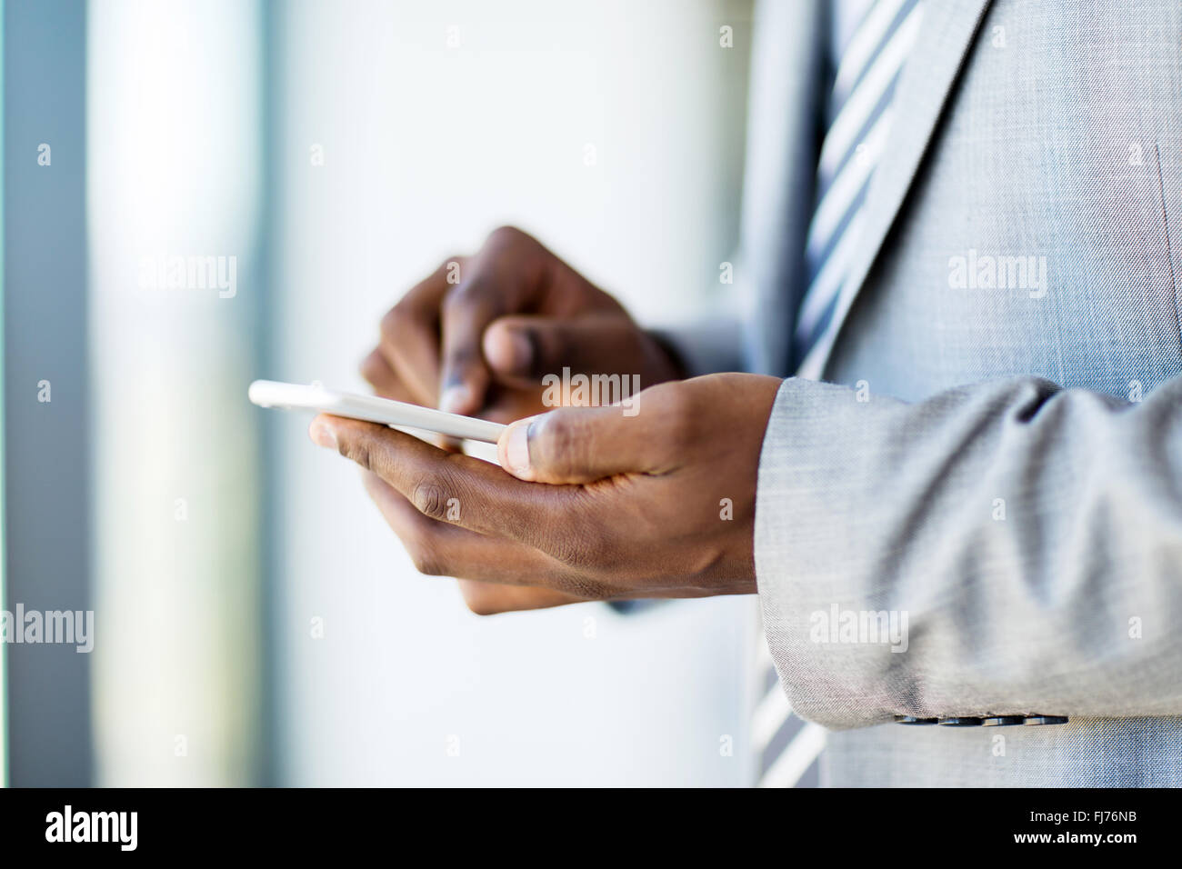 Nahaufnahme eines afrikanischen Geschäftsmann Hände SMS auf Smartphone Stockfoto