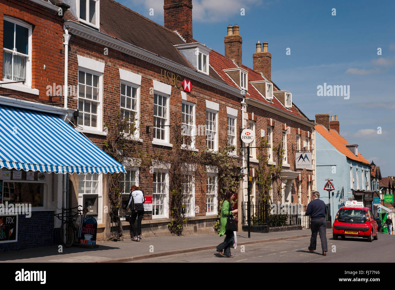 Stadtleben - unter blauem Himmel, Menschen Spaziergang Marktplatz (Malton, North Yorkshire, England) in der Nähe von historischen Gebäuden, Geschäften und der HSBC Bank. Stockfoto