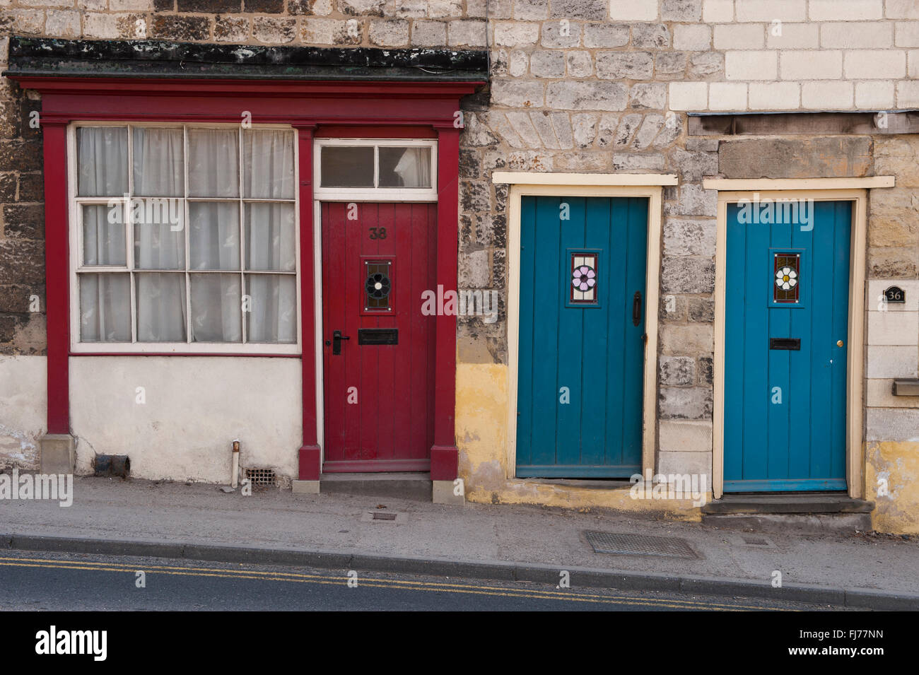 Drei Türen (1 rot, 2 blau) nebeneinander - gehören diese zu kleinen, malerischen Terrasse Hütten am alten Maltongate, Malton, North Yorkshire, England, Stockfoto