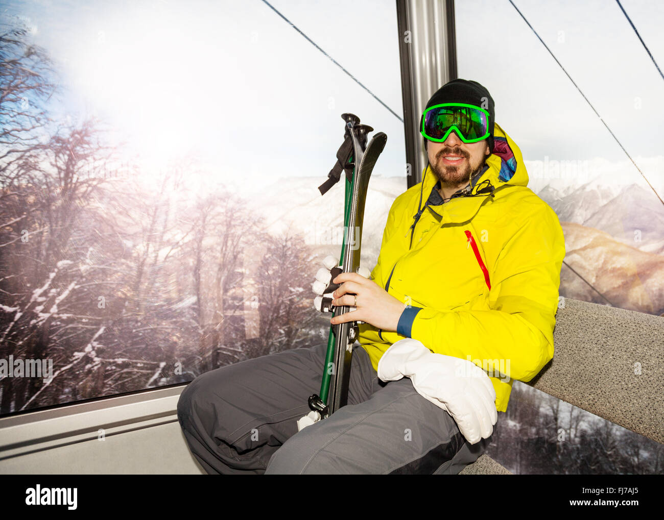 Mann Skifahrer im Skilift Seilbahn Kabine sitzen Stockfoto