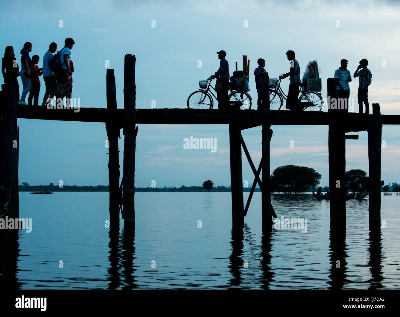 U Bein Bridge Taungthaman Lake Amarapura Myanmar // AMARAPURA, Myanmar — die U Bein Bridge erstreckt sich über den Taungthaman Lake in der Nähe von Mandalay. Die 1,2 Kilometer lange Teakholzkonstruktion, die vermutlich die älteste und längste Teakholzbrücke der Welt ist, ist vom Himmel her umrahmt. Einheimische Fußgänger und Mönche überqueren die Brücke, während Touristen die berühmte Szene beobachten, die besonders bei Sonnenuntergang beliebt ist. Stockfoto