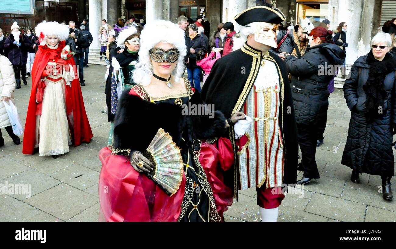 Paare gehen zusammen mit aufwendigen venezianischen Masken und Kostüme während der jährlichen Karneval von Venedig in Venedig, Italien. Karneval läuft offiziell für 10 Tage auf die christliche Feier der Fastenzeit endet. Stockfoto