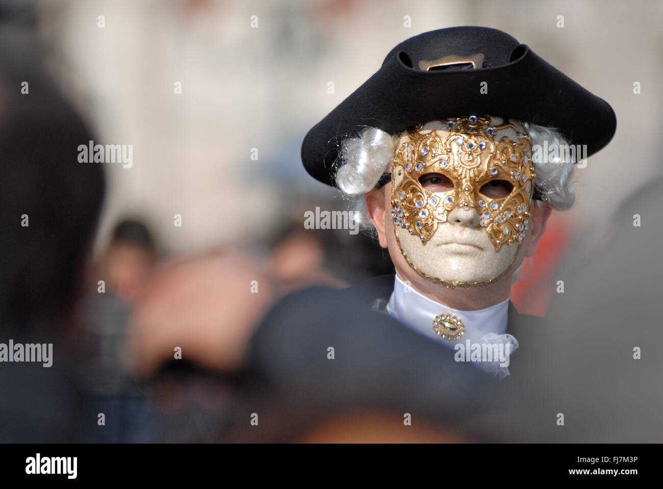 Ein Mann mit einer aufwendigen venezianische Maske und Kostüm während des jährlichen Karnevals von Venedig in Venedig, Italien. Karneval läuft offiziell für 10 Tage auf die christliche Feier der Fastenzeit endet. Stockfoto