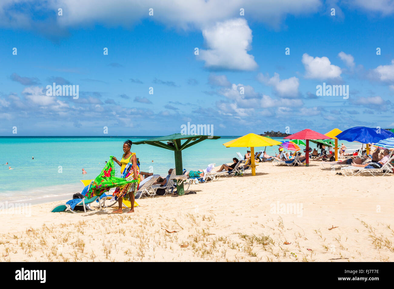 Lokale Frau verkaufen bunte Schals, wraps, Sarongs und Handtücher am Strand in Runaway Bay, nördlich von Antigua, Antigua und Barbuda Stockfoto