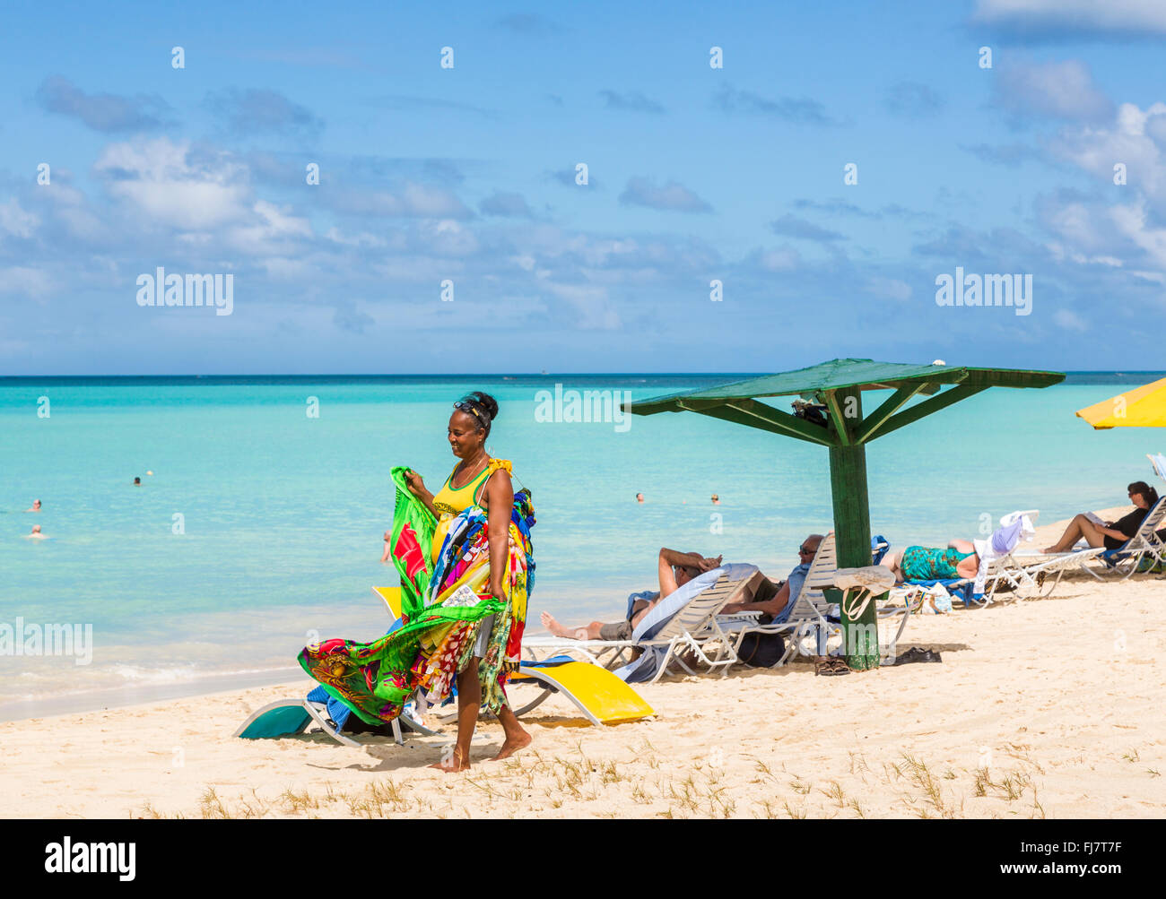 Lokale Frau verkaufen bunte Schals, wraps, Sarongs und Handtücher am Strand in Runaway Bay, nördlich von Antigua, Antigua und Barbuda Stockfoto