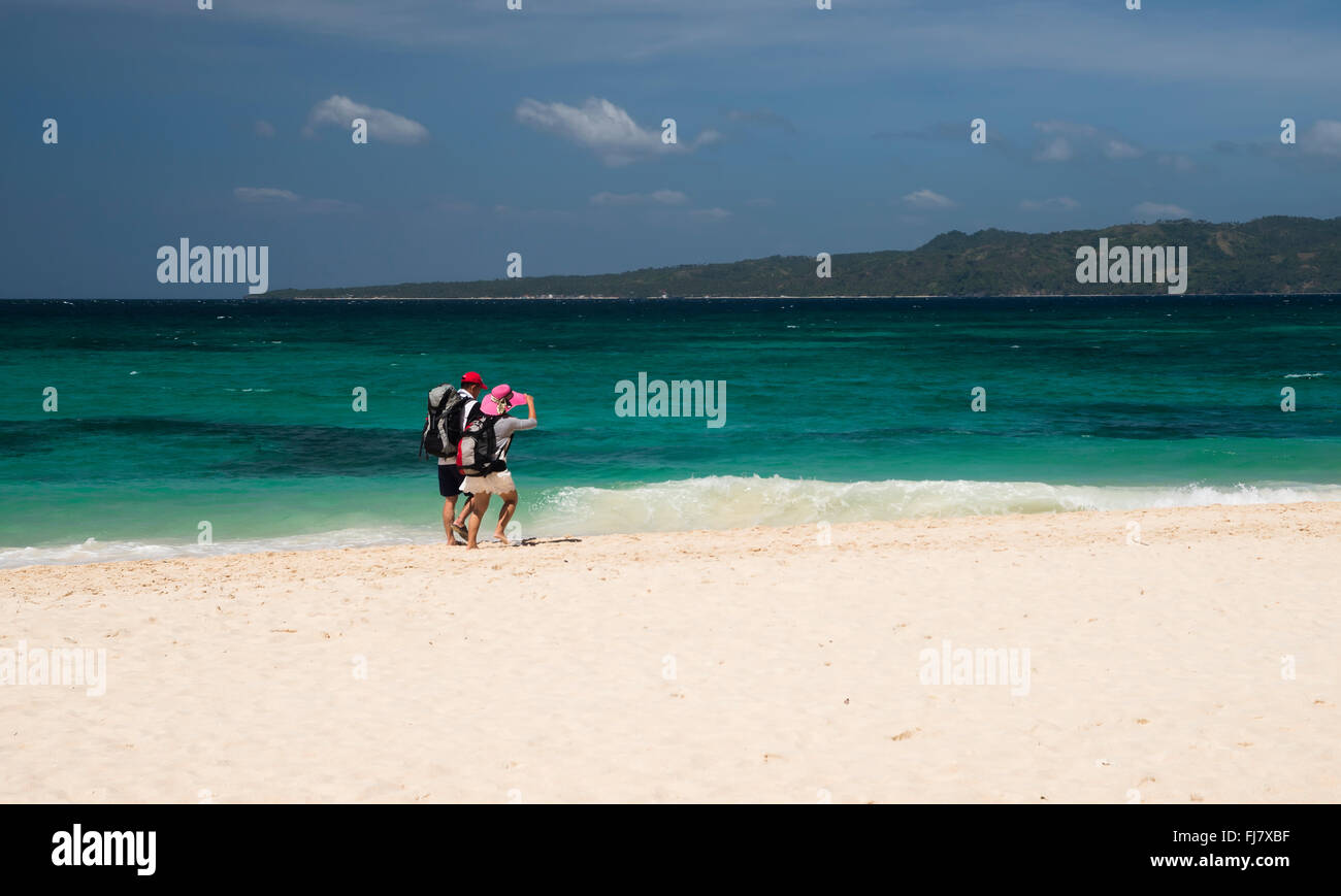 Boracay, Philippinen - 12. Februar 2016. Reisende zu Fuß am Strand Boracay Puka mit Rucksäcken. Stockfoto