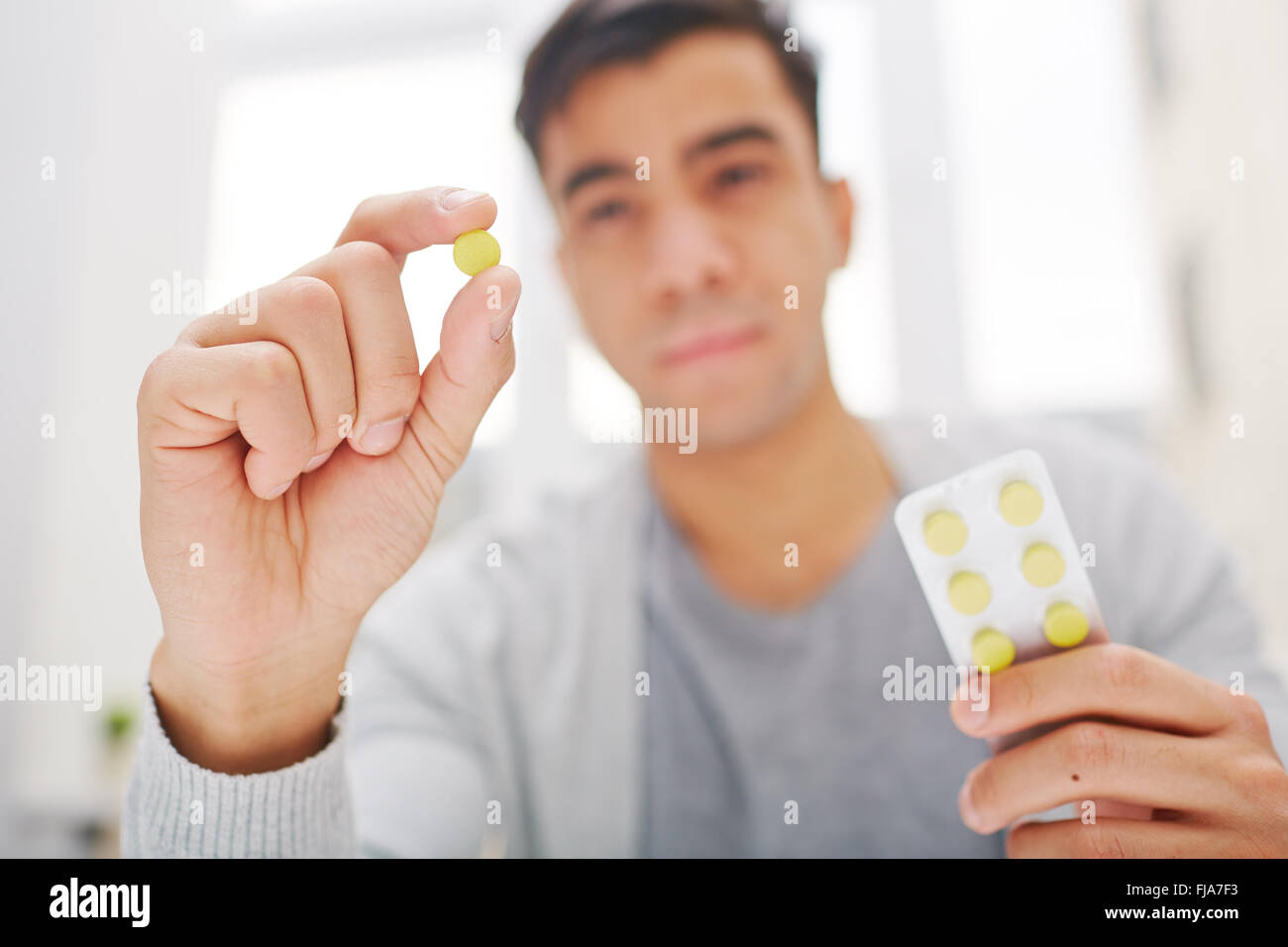 Junger Mann hält runde gelbe Pille Stockfoto