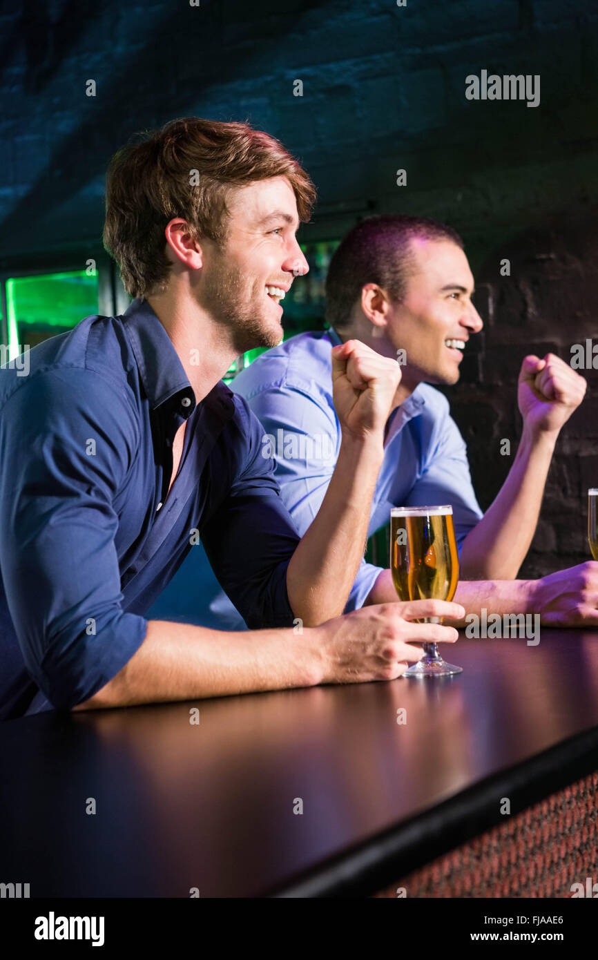 Zwei glückliche Männer Anhebung ihrer Faust beim Bier am Tresen Stockfoto