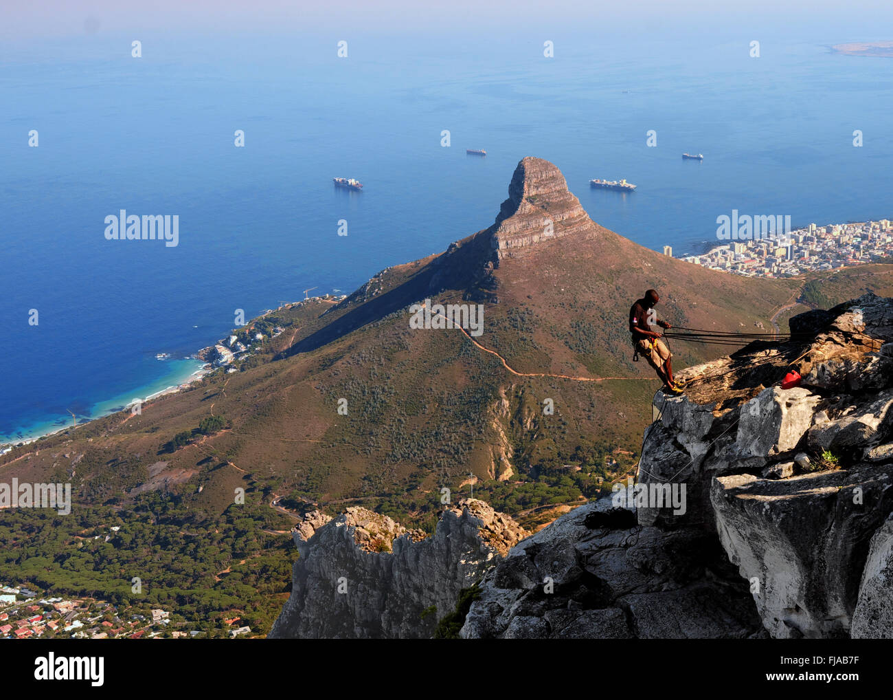 Mann, Vorbereiten der Tafelberg in Kapstadt, Abseilen mit Löwenkopf und dem Ozean im Hintergrund Stockfoto