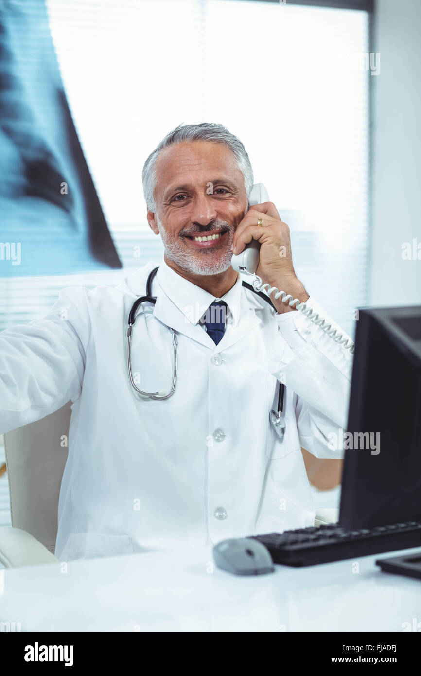 Arzt, Röntgen-Bericht während des Gesprächs am Telefon prüfen Stockfoto