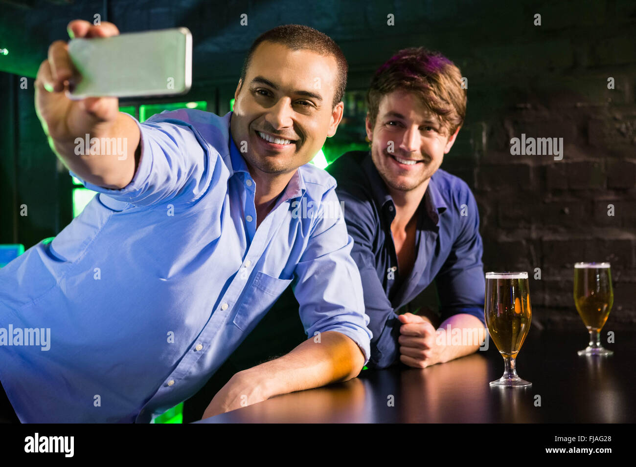 Zwei Männer, die eine Selfie auf Handy am Tresen Stockfoto