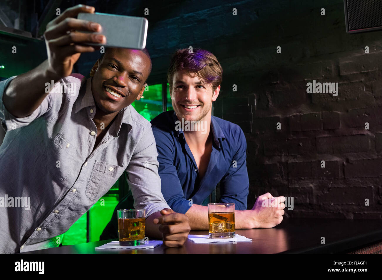 Zwei Männer, die eine Selfie auf Handy am Tresen Stockfoto