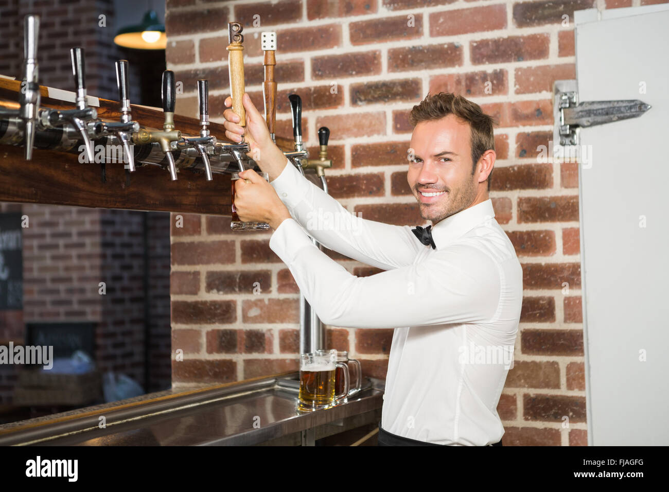 Gut aussehend Barkeeper einen Pint Bier in Strömen Stockfoto