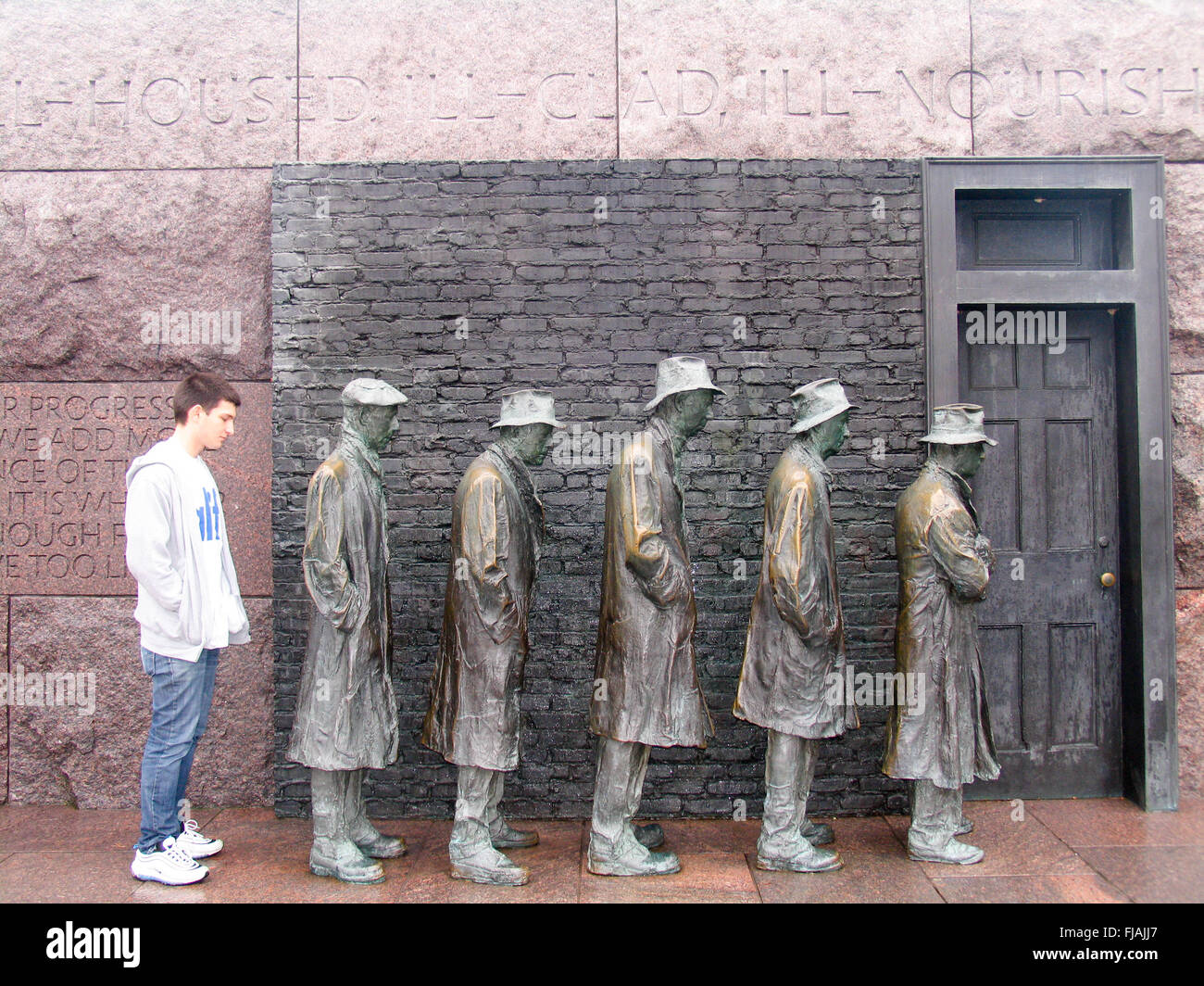 Ein junger Mann stand neben einer Skulptur, die Darstellung einer Szenenverlaufs aus der großen Depression, fünf Männer in einem Existenzminimum stehen. Stockfoto