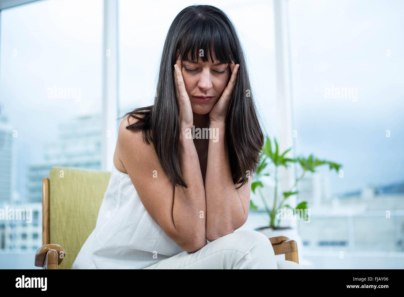 Schwangere Frau sitzend mit Kopfschmerzen Stockfoto
