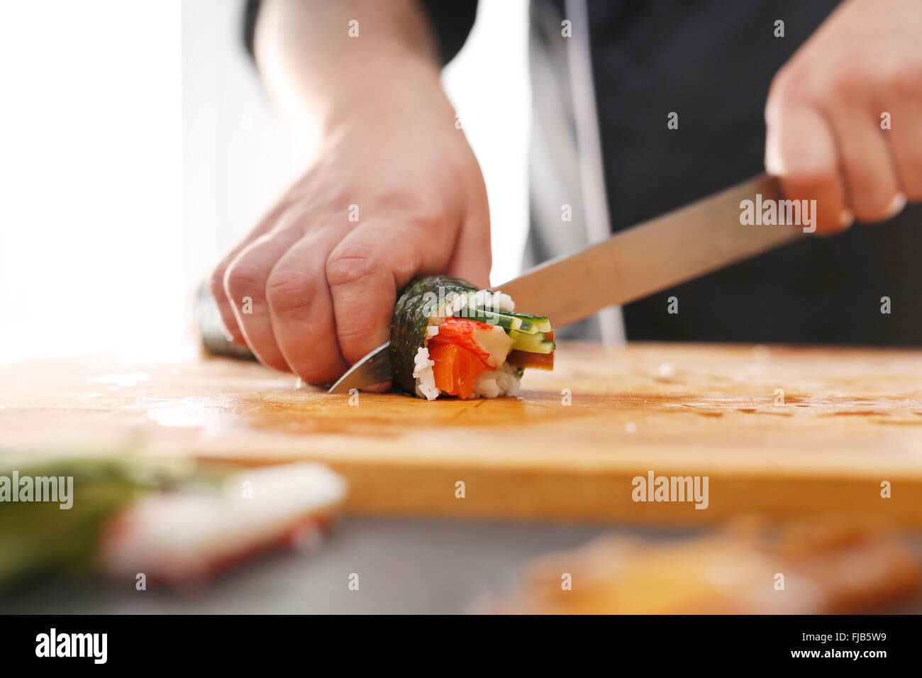 Japanisches Restaurant, Sushi-Teller. Sushi mit Lachs, Shrimps und Gurke. Meister Sushi Messer schneiden Sushi-Rollen Stockfoto