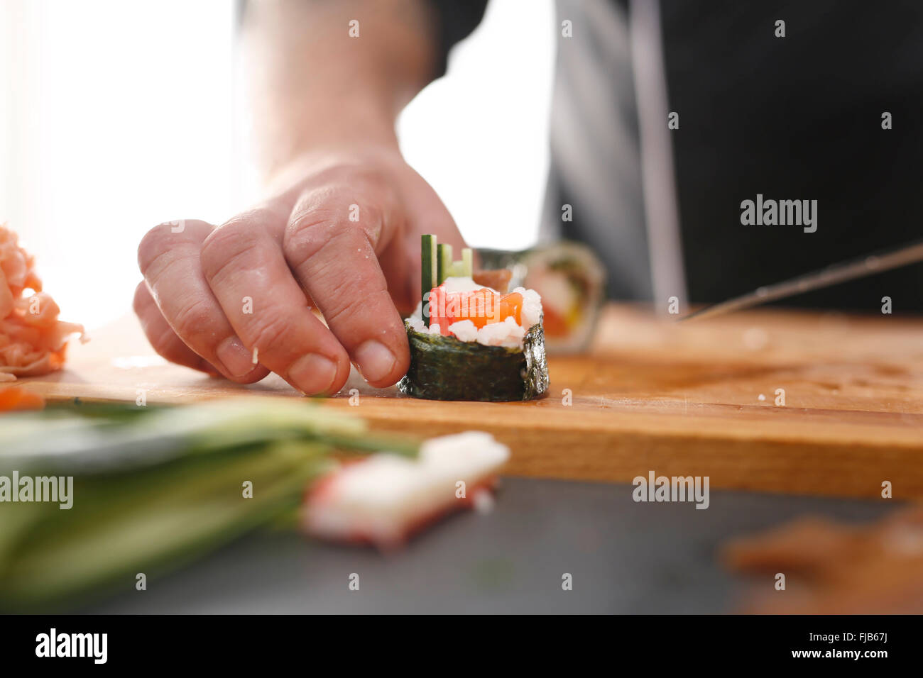 Japanisches Restaurant, Sushi-Teller. Sushi mit Lachs, Shrimps und Gurke. Meister Sushi Messer schneiden Sushi-Rollen Stockfoto