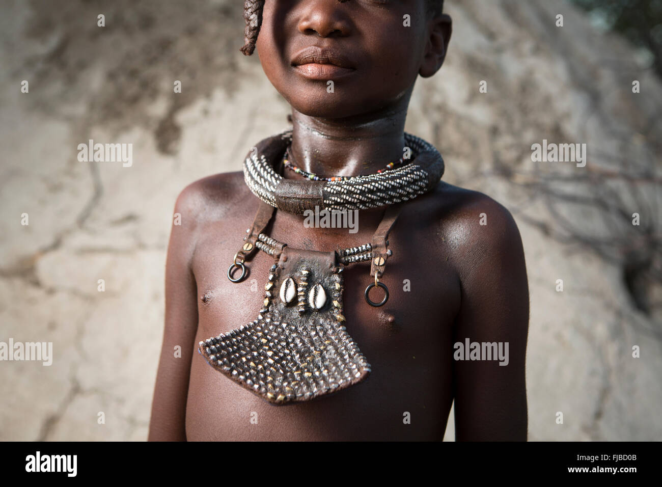 Ein Himba-Mädchen zeigt ihre traditionelle Verzierungen. Stockfoto