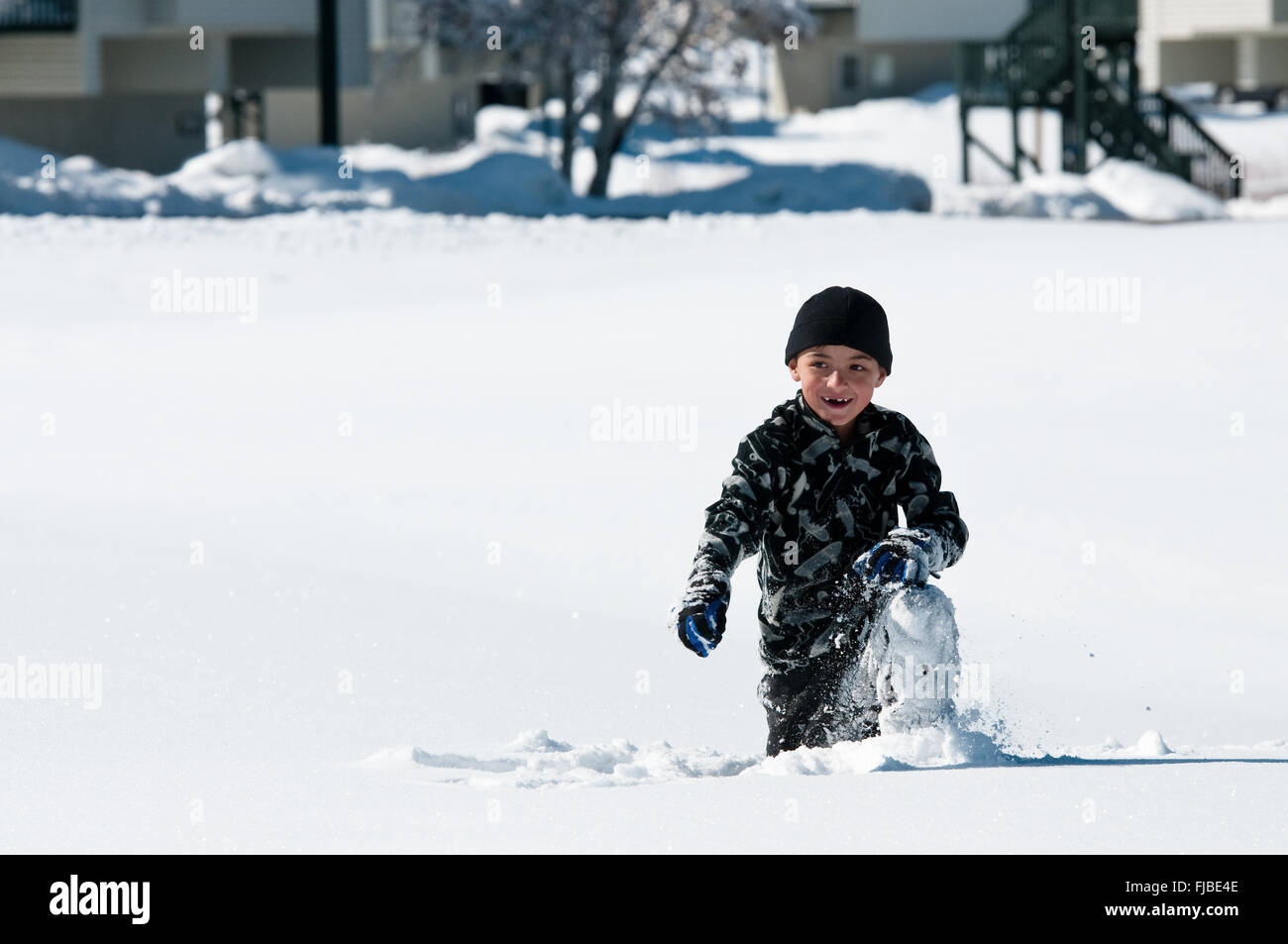 Entzückende kleine Junge kniend im Schnee spielen. Stockfoto