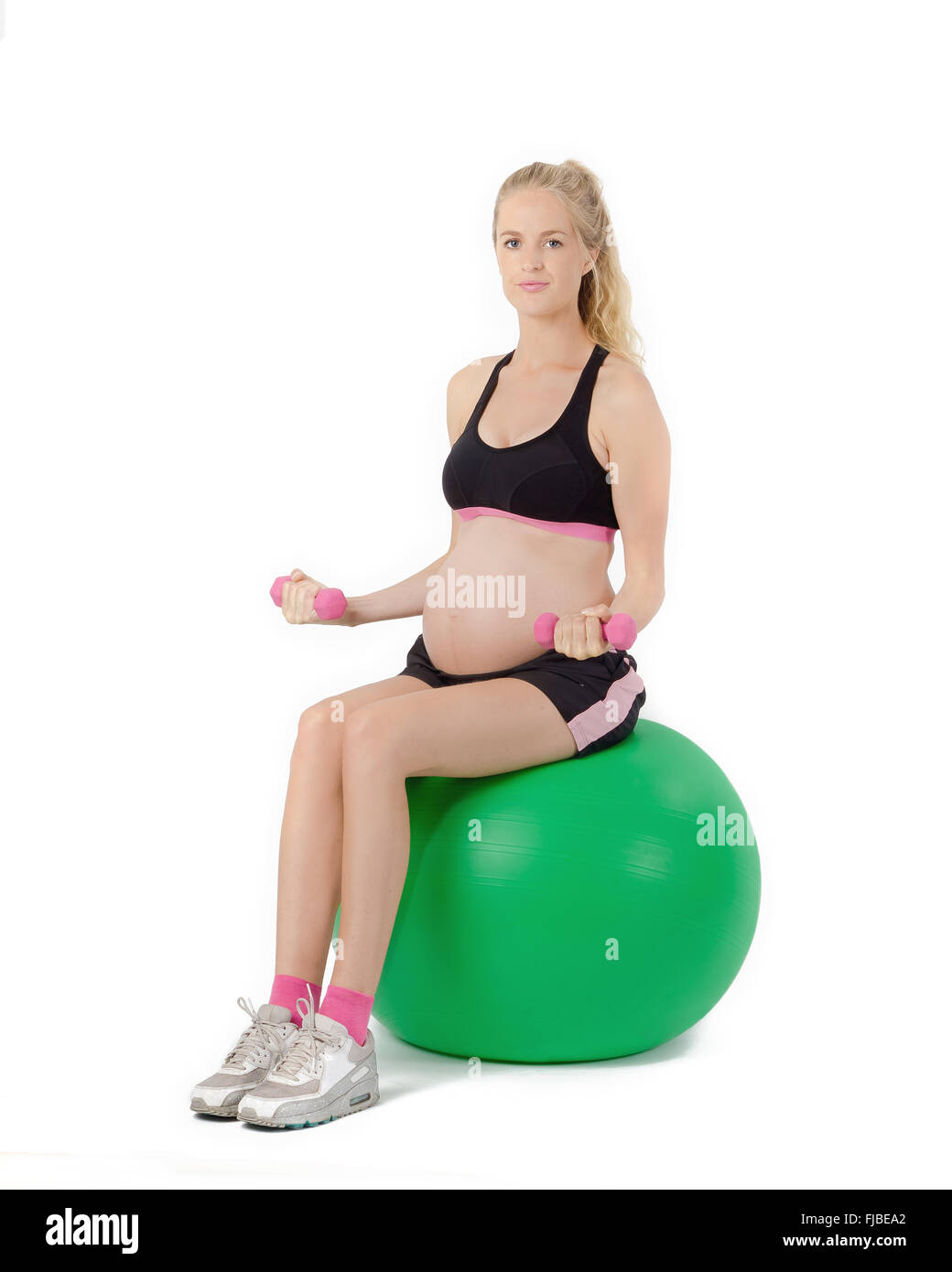 Schwangere Frau auf Yoga Balance Ball Bizeps Curl Übung mit Gewichten. Stockfoto