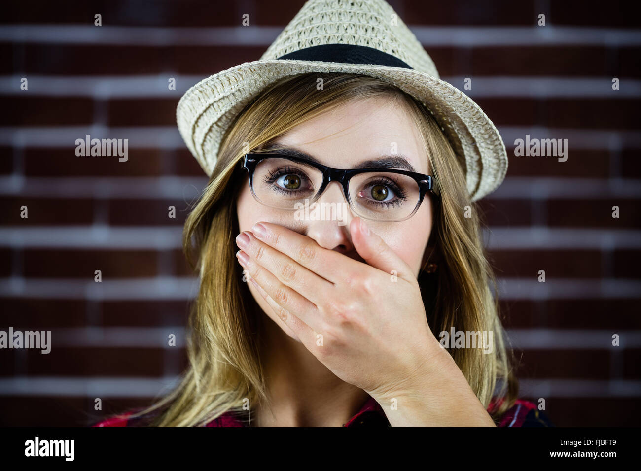 Hübsche blonde Frau, die ihr den Mund mit der hand Stockfoto