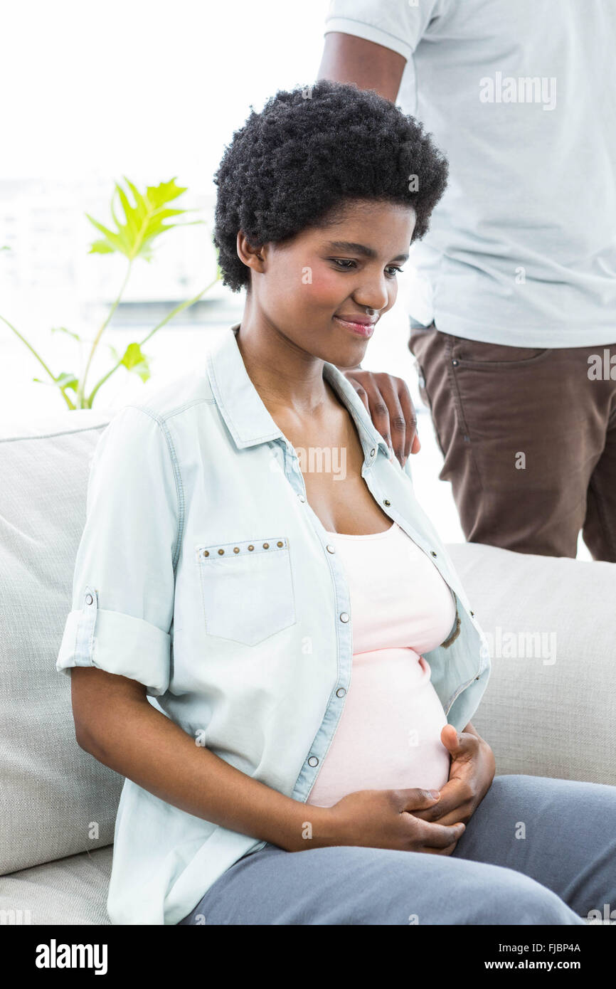 Schwangere Frau sitzend mit Hand auf Bauch Stockfoto