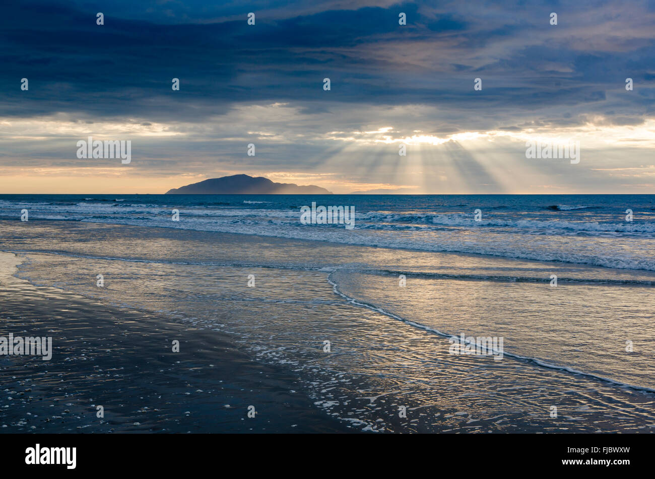 Abend Stimmung auf einem sandigen Strand, Wellen, Sonnenlicht durch dramatische Wolken strömen, Ost Küste, Nordinsel, Neuseeland Stockfoto