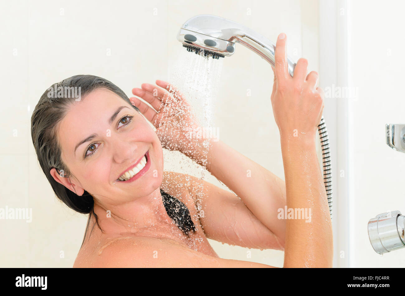 Glückliche Frau unter der Dusche genießen Wasser spritzt auf Ihr Stockfoto
