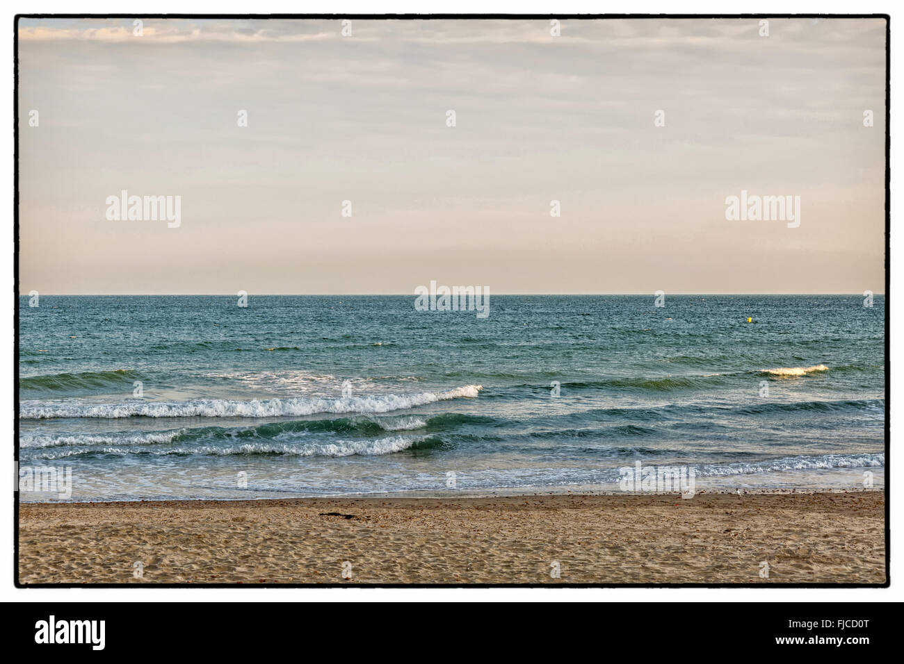 Ein farbiges Bild der goldenen Abendlicht mit rosa Tönung, Blick auf die Wellen am Strand mit Sand und einem keine Wolken in der sk Stockfoto