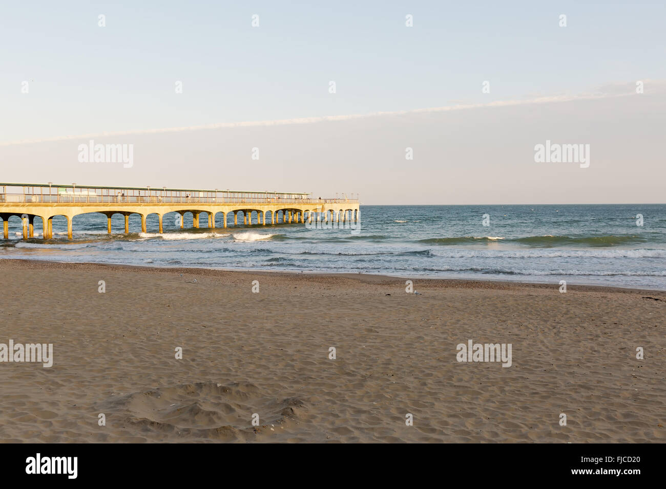 Goldene Abendlicht einer Silhouette eines Surfers auf seinem Brett, das Meer am Strand mit Sand und keine Wolken in Richtung der Stockfoto
