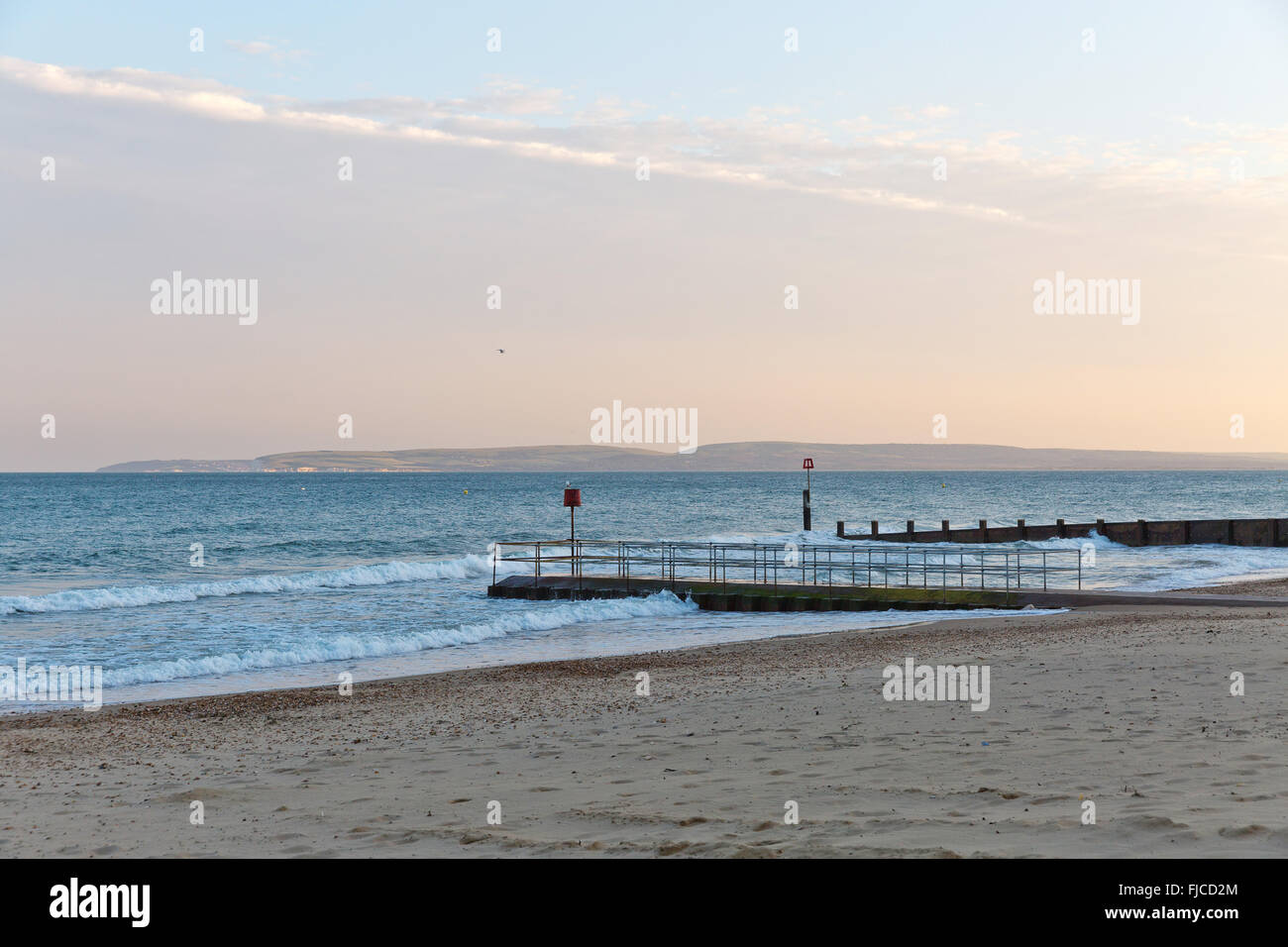 Goldene Abendlicht eines Vogels fliegen in den Himmel am Meer, Blick auf einem Steg am Strand mit Sand und ein Flugzeug rosa Col getroffen Stockfoto
