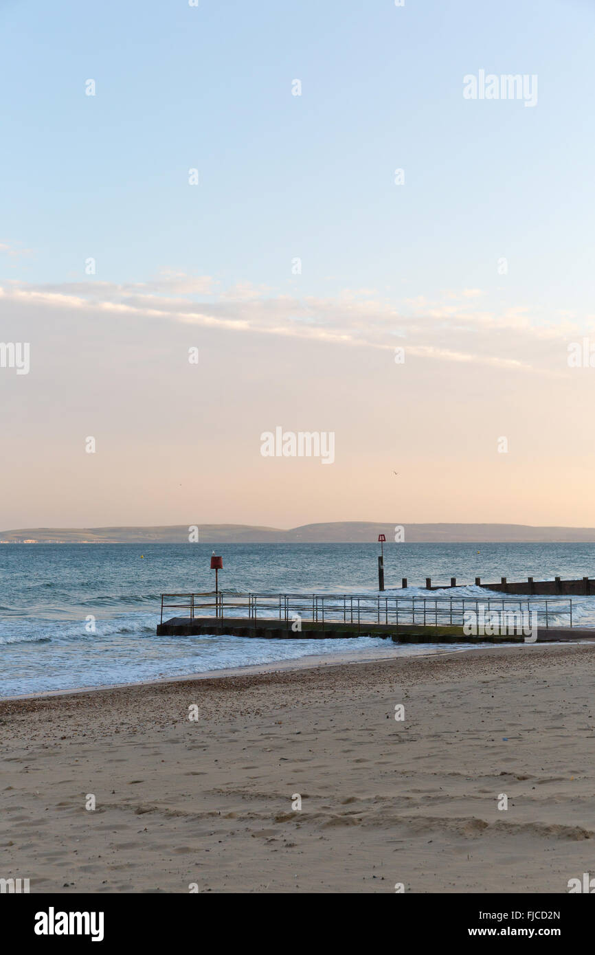 Goldene Abendlicht eines Vogels fliegen in den Himmel am Meer, Blick auf einem Steg am Strand mit Sand und ein Flugzeug rosa Col getroffen Stockfoto