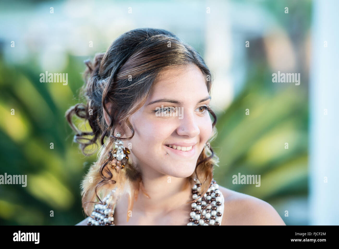Lächeln von einem schönen Mädchen mit Ohrringen mit Federn Stockfoto