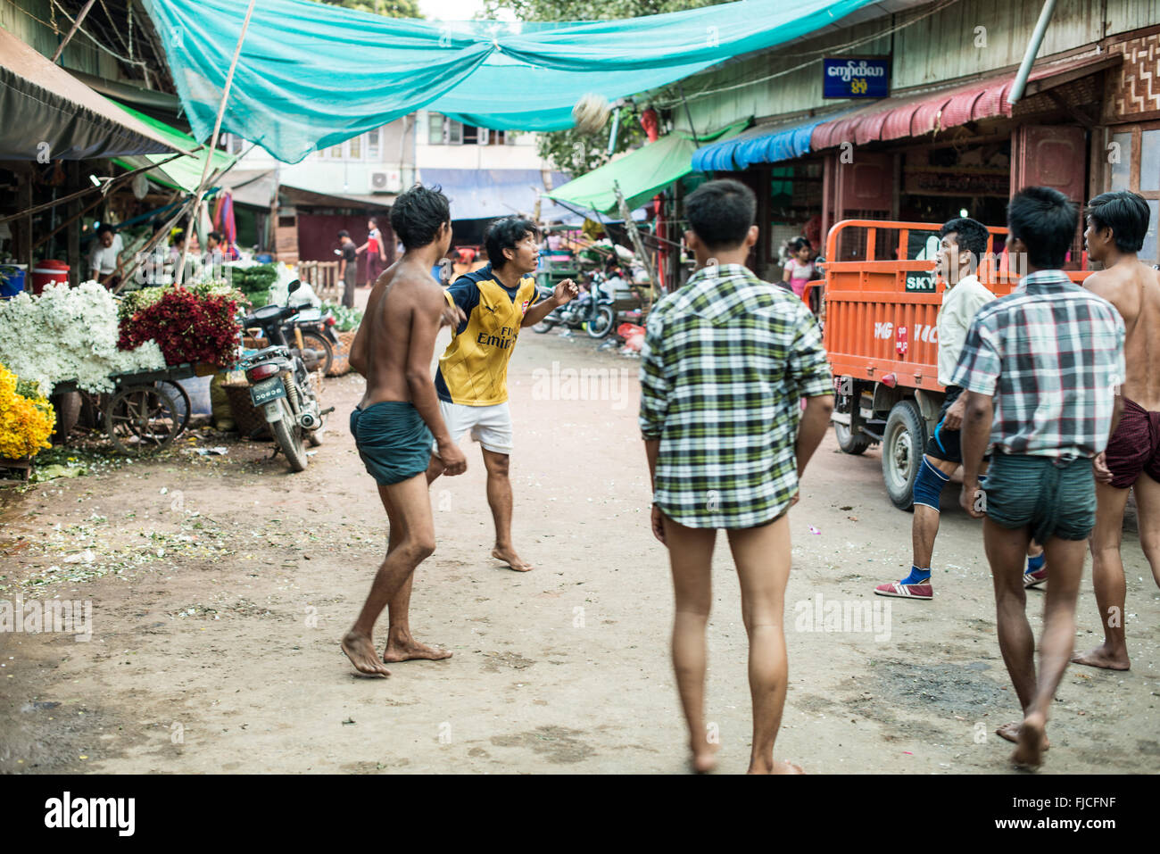 MANDALAY, Myanmar – Eine Gruppe birmanischer Männer spielt auf einer belebten Straße in Mandalay, Myanmar, ein lebhaftes Spiel von Chinlone, auch bekannt als Caneball. Dieser traditionelle Sport, der für Myanmars kulturelle Identität von zentraler Bedeutung ist, erfordert Geschicklichkeit und Teamarbeit – Eigenschaften, die den Gemeinschaftsgeist fördern. Stockfoto