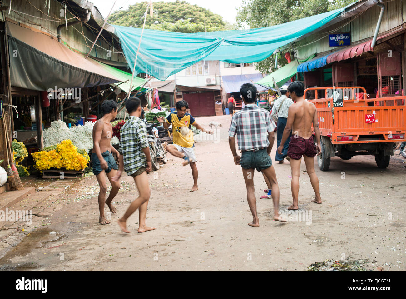 MANDALAY, Myanmar – Eine Gruppe birmanischer Männer spielt auf einer belebten Straße in Mandalay, Myanmar, ein lebhaftes Spiel von Chinlone, auch bekannt als Caneball. Dieser traditionelle Sport, der für Myanmars kulturelle Identität von zentraler Bedeutung ist, erfordert Geschicklichkeit und Teamarbeit – Eigenschaften, die den Gemeinschaftsgeist fördern. Stockfoto