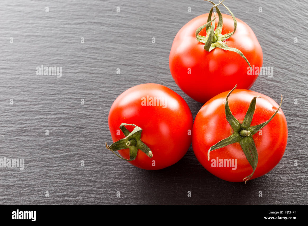 Tomaten auf einem schwarzen Stein Hintergrund. Stockfoto